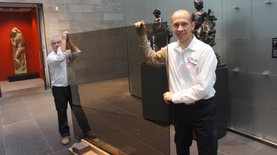 Two professional glaziers installing a large glass panel in a commercial building in Melbourne